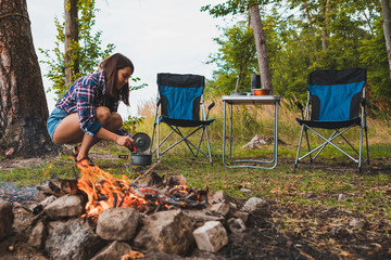 Wall Mural - couple resting near bonfire. woman cooking outdoors on fire