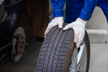 Wall Mural - mechanic in uniform is check the quality of rubber wheels that have been used. while working in car repair center.