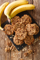 Wall Mural - Vegetarian banana cookies with oatmeal and nuts close-up on the table. Vertical top view