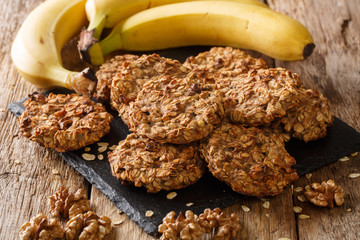 Wall Mural - Homemade low-calorie banana cookies with oatmeal and walnuts close-up on a slate board. horizontal