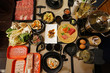 A table full of prepared plates of fresh vegetables, sliced Wagyu beef, pork meat, Sushi and Sashimi for Shabu Shabu (Japanese hot pot)