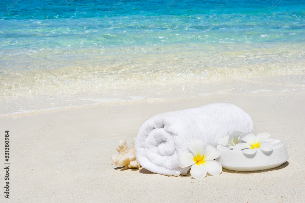 White spa towel and flowers on sandy tropical sea beach