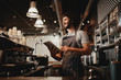 © StratfordProductions - Cheerful young caucasian cafe owner wearing apron using digital tablet