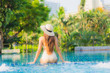 © siraphol - Portrait beautiful young asian woman relax around swimming pool in hotel resort