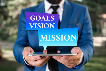 Poster - Word writing text Goals Vision Mission. Business photo showcasing practical planning process used to help community group Businessman in blue suite with a tie holds lap top in hands