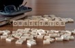 obstetrics concept represented by wooden letter tiles on a wooden table with glasses and a book