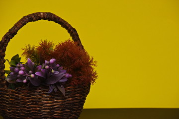 two artificial branches with berries and needles in a basket