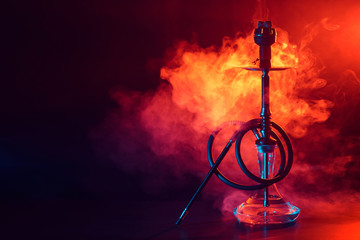 hookah shisha with glass flask and metal bowl with colored smoke on a black background