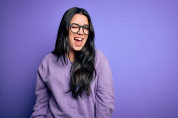 Poster - Young brunette woman wearing glasses over purple isolated background winking looking at the camera with sexy expression, cheerful and happy face.