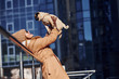 © standret - Woman in warm clothes have holding her little pug dog on hands near business building that on background