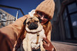 © standret - Woman in warm clothes make selfie with her little pug dog near business building that on background