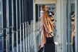 © standret - Young female passenger in warm clothes walking with her dog in airport hall