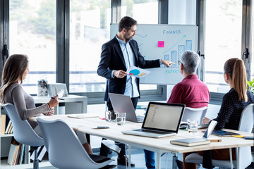 Handsome businessman explaining a project to his colleagues on coworking place.