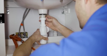 Wall Mural - plumber installing sink siphon in domestic bathroom