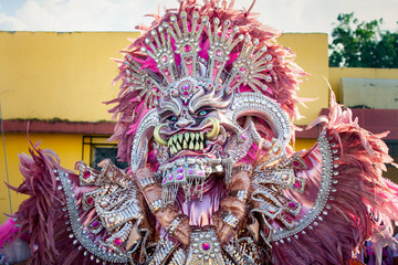 closeup man in vivid pink costume poses for photo on city street at dominican carnival