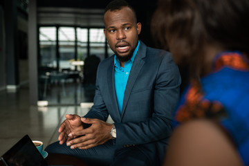 black african businessman discussing work on a digital tablet during a casual meeting together over 