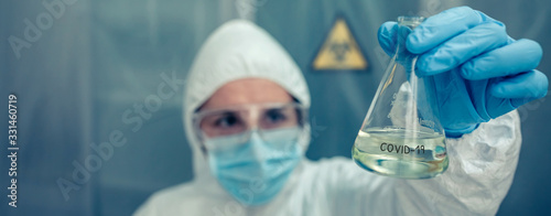 Cuadros en Lienzo Female scientist with bacteriological protection suit looking test tube in the laboratory
