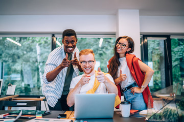 Wall Mural - Cheerful multiracial colleagues smiling and pointing at camera