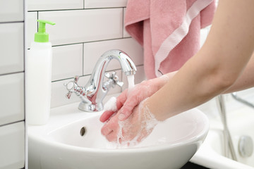 Washing hands with liquid soap under running water to protect against a dangerous virus. Health concept. Close-up.