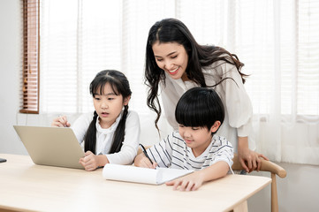 asian mother are looking care her son and daughter, they are do their homework the mother teach them