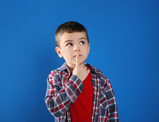 Thoughtful little boy in casual outfit on blue background