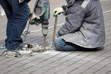 Workers repair the road surface with a jackhammer. Construction work, laying of paving slabs