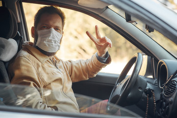 a man driving a car puts on a medical mask during an epidemic, a taxi driver in a mask, protection from the virus