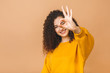 © denis_vermenko - Close-up photo of funny curly young brunette woman in casual showing OK gesture, looking at camera, isolated on beige background.