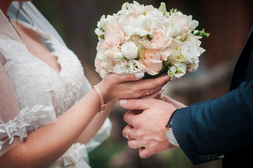 Groom and bride holding colorfull wedding bouquet in the hand