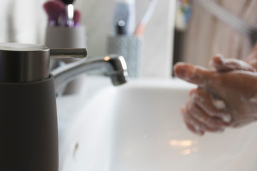 Wall Mural - Person washing his hands with soap and water on sink to prevent diseases.