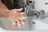 Fototapeta  - Person washing his hands with soap and water on sink to prevent diseases.