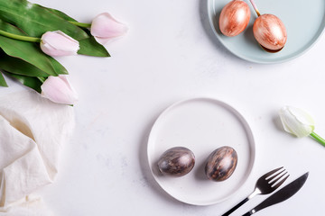 Wall Mural - Greeting Easter card with handmade painted bright eggs on a plates and tulips flowers on a light grey marble background.