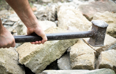 big hammer in the hands of a man and stones close-up