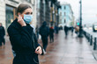 © ANR Production - Prevention of coronavirus outbreak in 2020. Portrait of young european woman wearing a mask in the city street. Prevent pollution and disease concept.