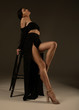 © lashkhidzetim - Elegant beautiful woman with long legs in black fashionable dress posing in studio on grey background.
