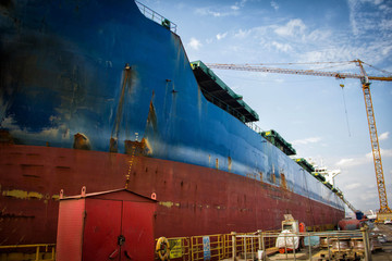 Poster - A large tanker cargo ship is being renovated and painted in shipyard dry dock.