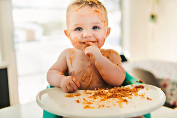 Little baby boy eating her dinner and making a mess