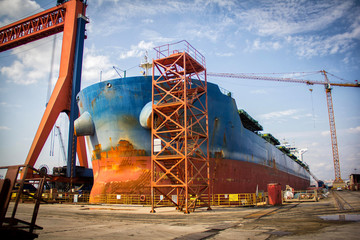 Poster - A large tanker cargo ship is being renovated and painted in shipyard dry dock.