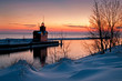 The Holland Harbor South Pierhead Lighthouse, also known as Big Red, stands guard on the icy shore of Lake Michigan at twilight.