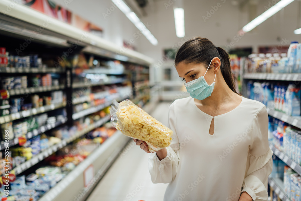 Shopping during an epidemic.Buyer wearing a protective mask.Nonperishable smart purchased household pantry groceries.Pandemic quarantine preparation.Dry goods and nutritional foods shopping.Expiration - obrazy, fototapety, plakaty 