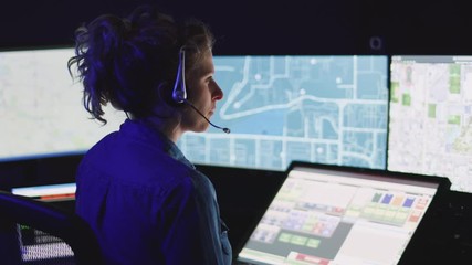 Emergency dispatcher focuses on her computer screens while hard at work