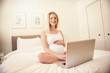 © Louis-Paul Photo - Attractive young pregnant woman with laptop on bed