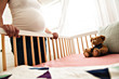 View at pregnant woman belly close to baby crib