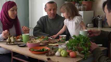 Wall Mural - Muslim family having a Ramadan feast. Arab husband and wife, man and woman, children boy and girl, daughter and son eating dinner together at home