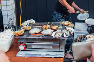 Cooking grilled seashells at Japanese summer festival