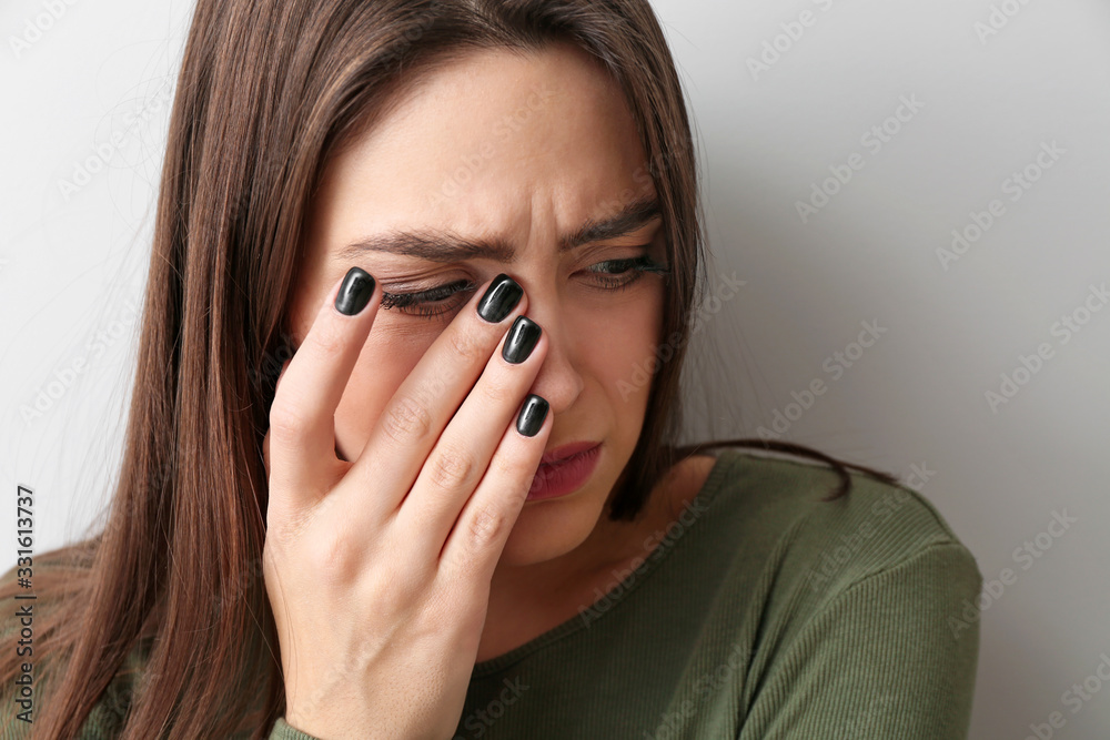Depressed young woman on light background
