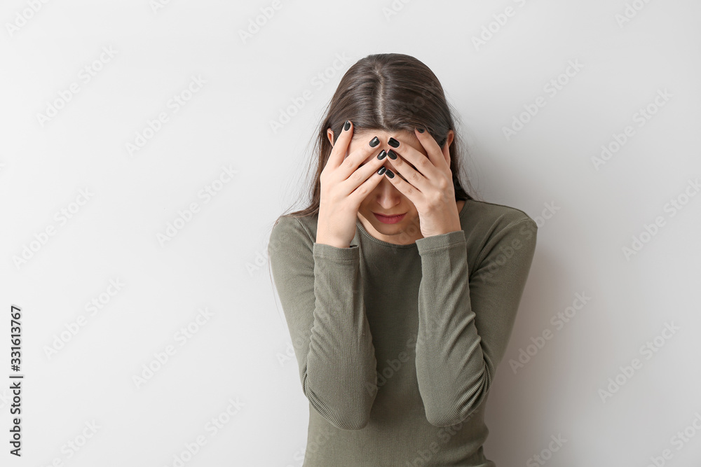 Depressed young woman on light background