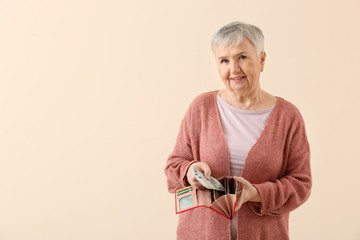 Wall Mural - Senior woman with wallet on color background