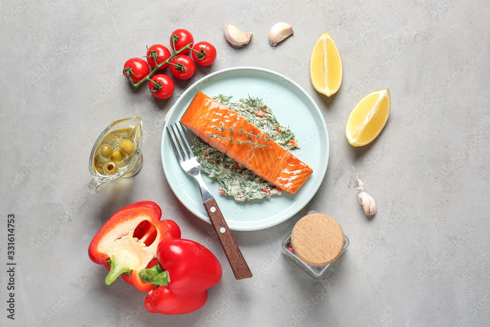 Plate with cooked salmon fillet and sauce on grey background