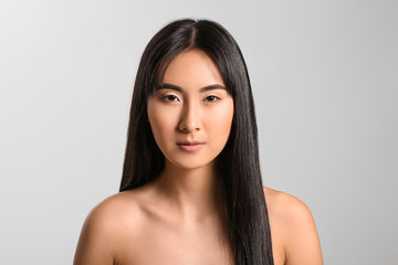 Wall Mural - Young Asian woman with beautiful long hair on grey background